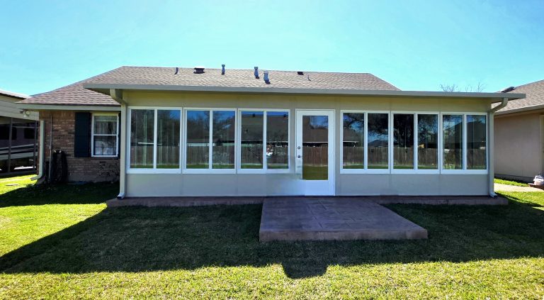 Insulated sunroom with large glass windows and a concrete patio, designed for comfort in New Orleans' subtropical climate.