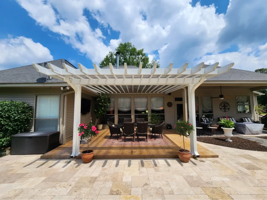 Patio cover with white beams providing shade over a wooden deck, featuring outdoor seating and potted plants, enhancing backyard comfort in New Orleans.